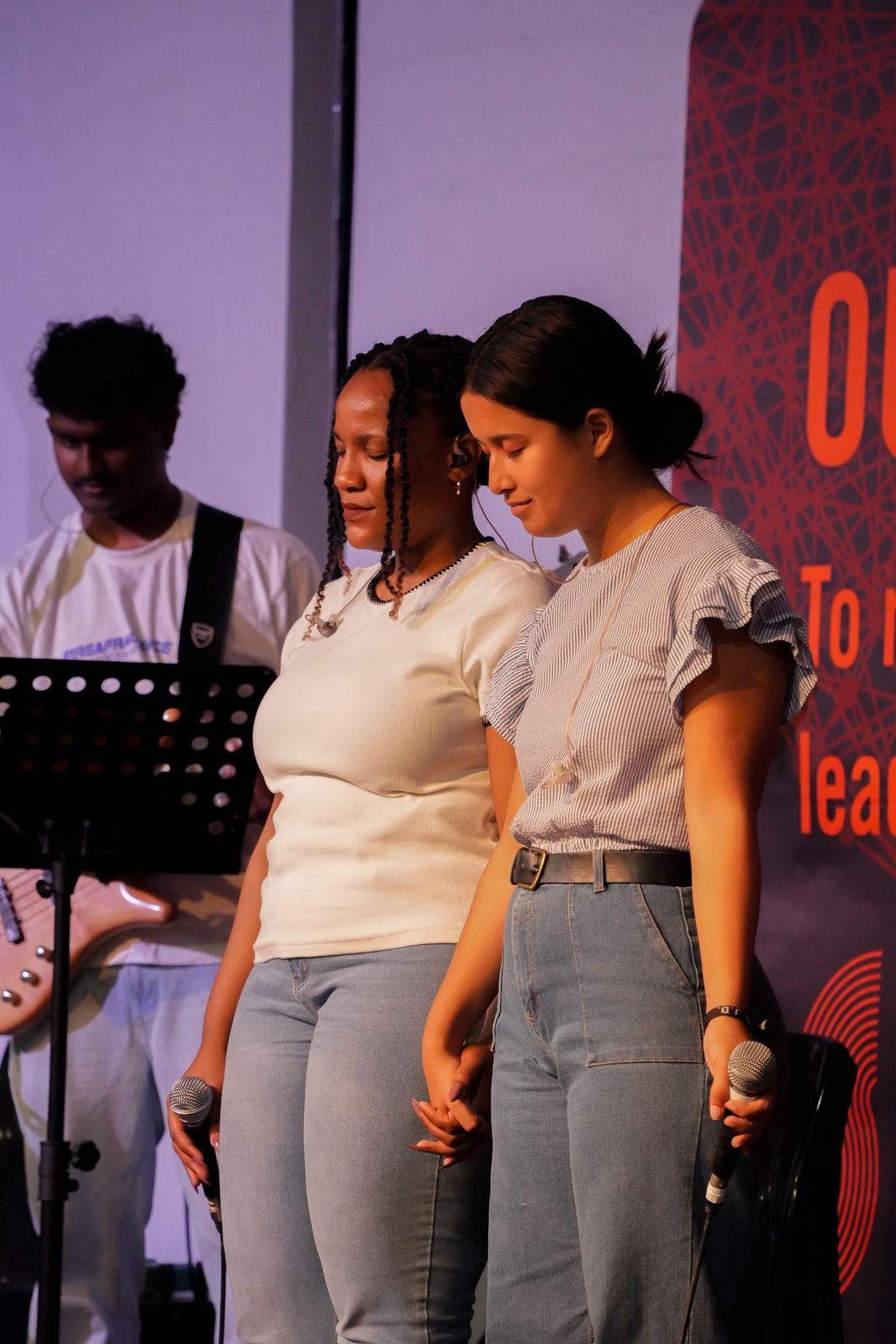 Two young women worshipping together with microphones