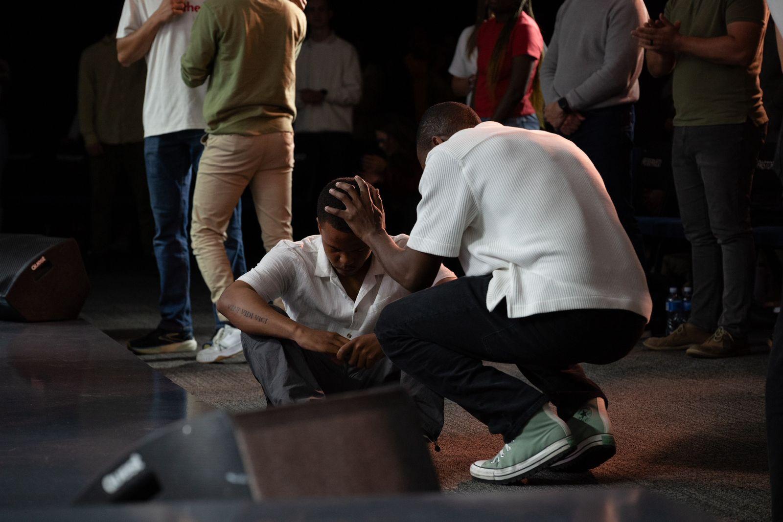 Young adults praying together with hands raised